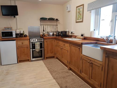 uma cozinha com armários de madeira e um forno com placa de fogão em Forest Farm Papplewick Nottingham - Spacious Self-Contained Rural Retreat! em Papplewick