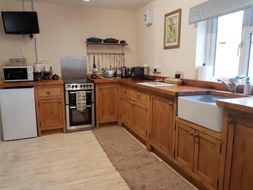 La cuisine est équipée de placards en bois et d'un four avec plaques de cuisson. dans l'établissement Forest Farm Papplewick Nottingham - Spacious Self-Contained Rural Retreat!, à Papplewick