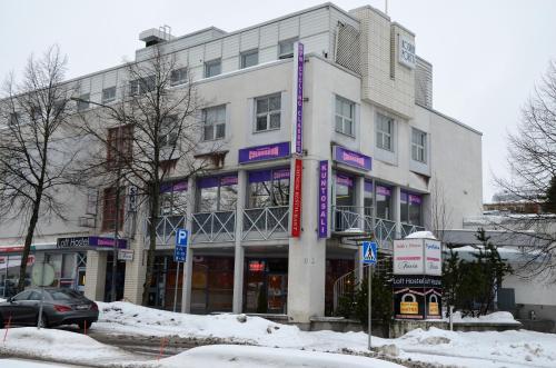 a white building with purple signs on it in the snow at Loft Family Hotel in Imatra