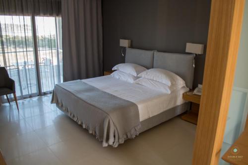 a bedroom with a bed with a view of a balcony at Double Bay Beach Hotel in Elafonisos