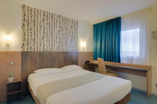 Schlafzimmer mit einem Bett, einem Schreibtisch und einem Fenster in der Unterkunft Brit Hotel Hermes in Couchey