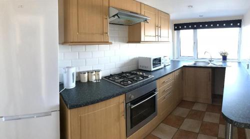 a kitchen with wooden cabinets and a stove top oven at South Beach Apartment in Ardrossan