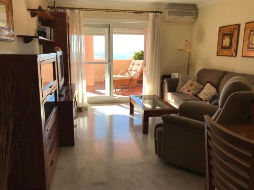 ein Wohnzimmer mit einem Sofa und einem TV in der Unterkunft Sub-ático con parking en el centro de Estepona in Estepona