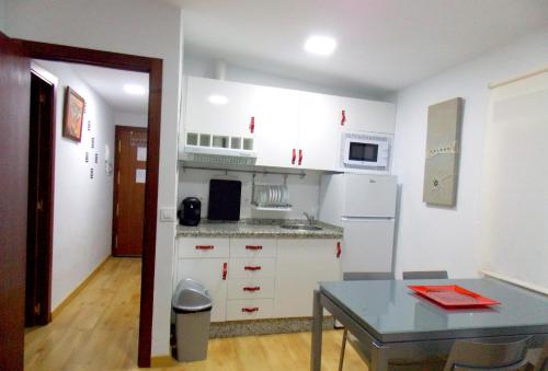 una cocina con armarios blancos y una mesa con una mesa. en Apartamentos Capuchinas, en Plasencia