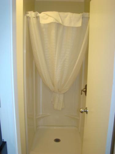 a bathroom with a shower with a curtain and a toilet at Paddock Inn in Coleman