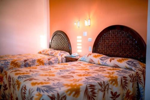 two beds in a room with orange walls at Hotel Los Girasoles in Tepic