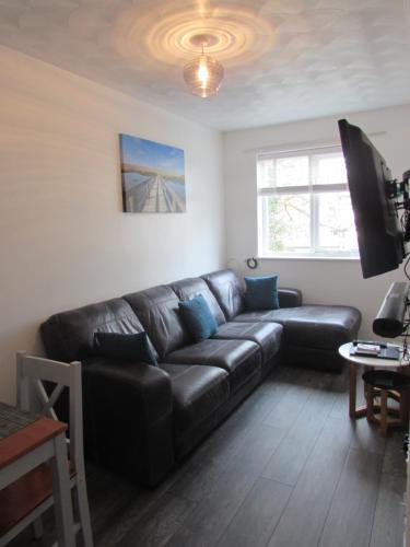 a living room with a black leather couch and a tv at The Annex Apartment in Weymouth