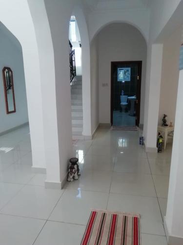 a hallway with a white tile floor and a staircase at Heather's Retreat in Brufut