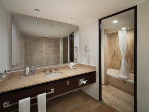 a bathroom with a sink and a large mirror at El Cid Castilla Beach in Mazatlán