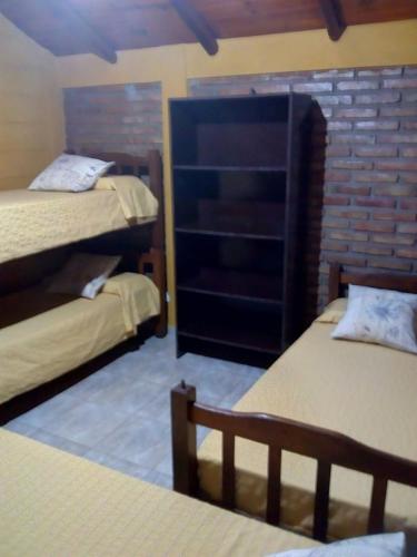 a room with two beds and a brick wall at Cabañas Buen Dia in Villa Serranita