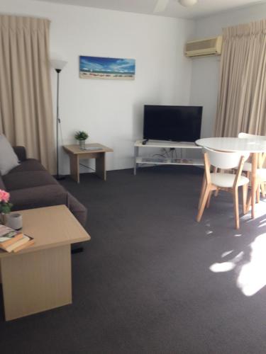 a living room filled with furniture and a tv at Chez Noosa Resort Motel in Sunshine Beach