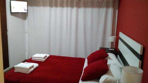 a bedroom with a red bed with towels on it at Check in Angeles Bahía in Bahía Blanca