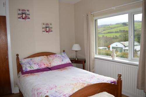 a bedroom with a bed and a window with a view at Drumahaman Cottage in Ballycastle