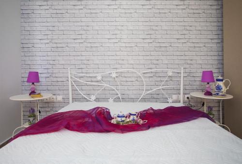 a bed with a red blanket and two tables with lamps at Ble on Blue in Athanion