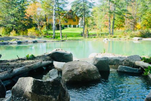 a pond with rocks in front of a house at Le Domaine du Lac Saint Charles in Quebec City
