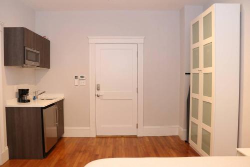 a small kitchen with a white door and a sink at A Stylish Stay w/ a Queen Bed, Heated Floors.. #15 in Brookline
