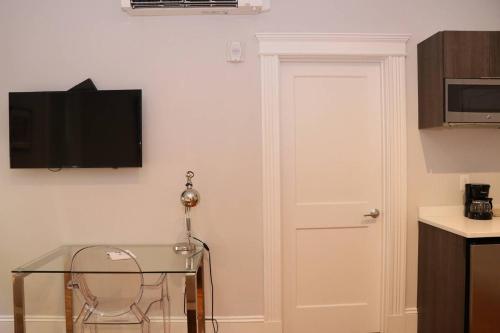 a room with a table and a door with a television on the wall at A Stylish Stay w/ a Queen Bed, Heated Floors.. #15 in Brookline