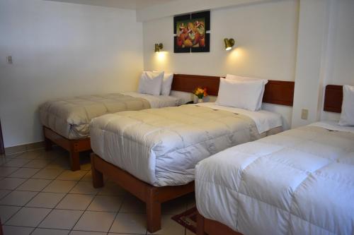 a hotel room with two beds with white sheets at Casa De Luz Hotel in Machu Picchu