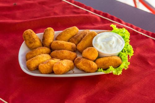 a plate of fried food with dipping sauce on a red table at Hotel Pousada Vivendas do Sol e Mar in Caraguatatuba