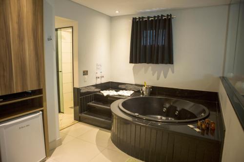 a bathroom with a large tub and a sink at Palais Hotel in São Vicente