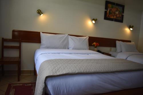 a hotel room with two beds and a chair at Casa De Luz Hotel in Machu Picchu