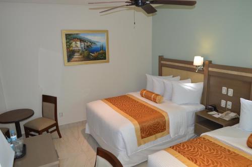 a hotel room with two beds and a chair at hotel villa magna poza rica in Poza Rica de Hidalgo