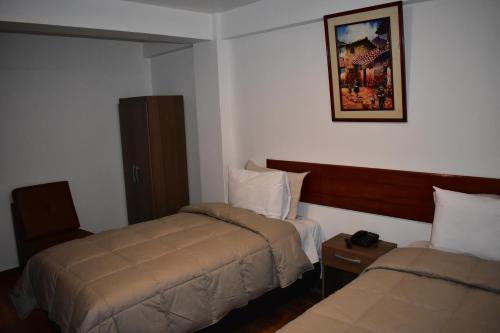 Habitación de hotel con 2 camas y una foto en la pared en Casa De Luz Hotel, en Machu Picchu