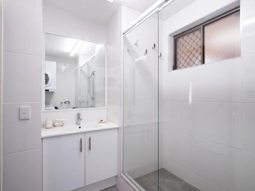 a white bathroom with a shower and a sink at Golden Shores U7 21 Landsborough Parade in Caloundra