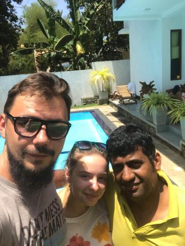 two men and a woman standing next to a swimming pool at Blue Water hikkaduwa in Hikkaduwa
