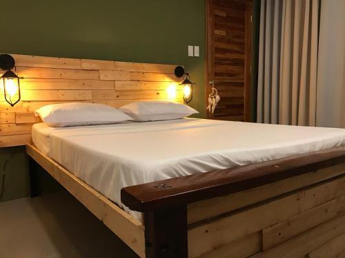 Bett mit einem Kopfteil aus Holz und 2 Kissen in der Unterkunft Michel'inn Coron in Coron