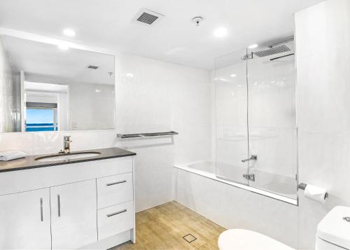 a white bathroom with a shower and a sink at Talisman Apartments in Gold Coast