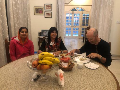 a group of people sitting at a table with a bowl of fruit at Jai Villa Homestay in Udaipur