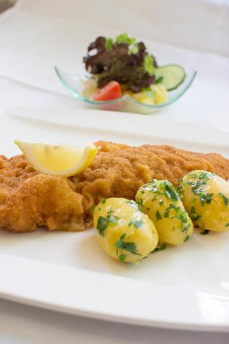 a plate of food with fish and potatoes with a lemon at Gastwirtschaft & Hotel Holzinger in Möllersdorf