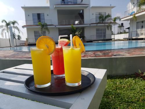 three drinks on a tray on a table near a pool at Sunstar Nilaveli in Trincomalee