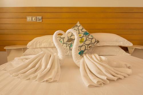 two swans towels are sitting on a bed at Trip Villa in Ukulhas