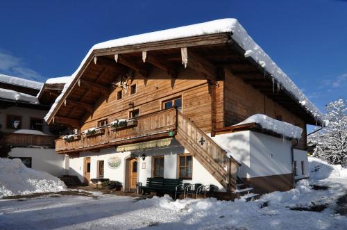 una baita di tronchi con neve sul tetto di Kaiserappartements Müllnerhof a Oberndorf in Tirol