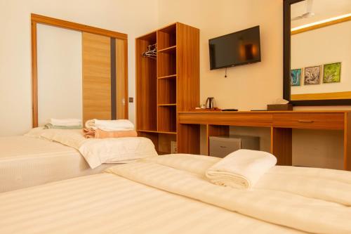 a hotel room with three beds and a television at Trip Villa in Ukulhas