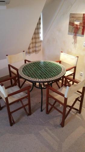 una mesa con 2 sillas y una mesa verde con sillas en Chambres touristiques La Cour Des Hôtes en Obernai