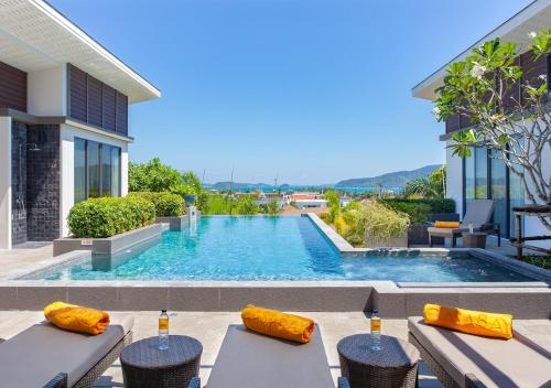 a swimming pool with tables and chairs in front of a house at CASABAY Luxury Pool Villas by STAY in Rawai Beach