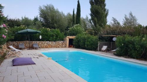 - une piscine avec des chaises et un parasol dans la cour dans l'établissement GRANDE MAISON - PISCINE - CALME - AIX EN PROVENCE, à Éguilles