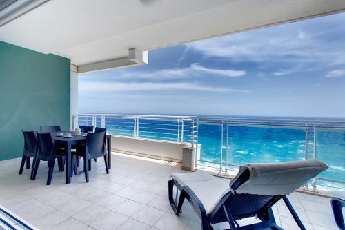 a balcony with a table and chairs and the ocean at Seafront Apartment Sliema in Sliema