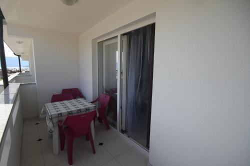 Una habitación con una mesa y sillas y un balcón. en Apartments Mare, en Baška