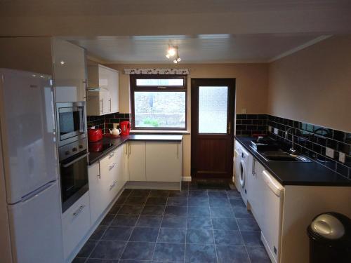 a large kitchen with white appliances and a window at Myrtle Cottage in Johnshaven