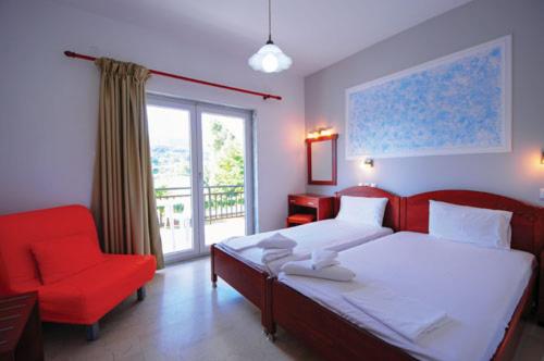 a bedroom with a bed and a red chair and a window at Hotel Afroditi in Paralia Panteleimonos