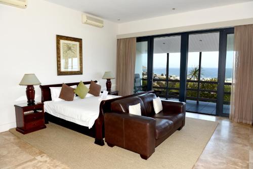 a bedroom with a bed and a leather chair at 51 On Camps Bay in Cape Town