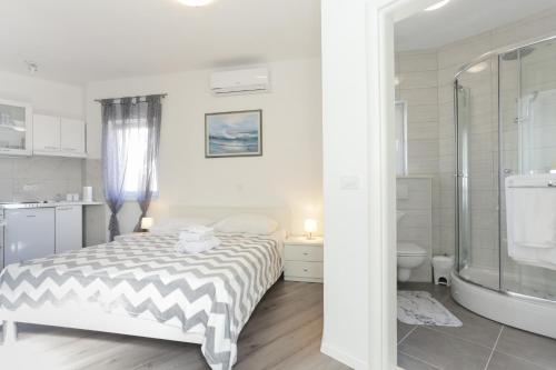 a white bedroom with a bed and a bathroom at Villa Supuk in Vinišće