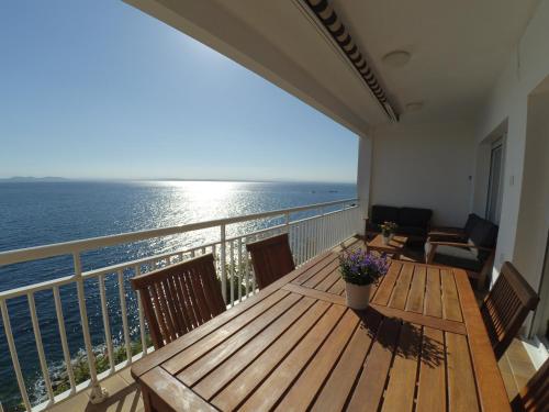 balcón con mesa de madera y vistas al océano en Apartament Belvedere, en Roses