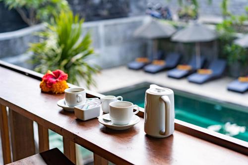 a table with cups and saucers sitting on a balcony at Bale Gede Lembongan in Nusa Lembongan