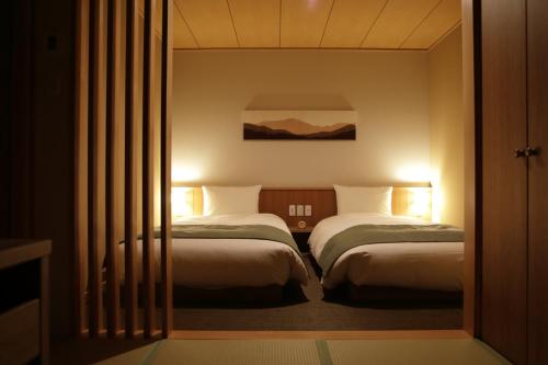 Habitación de hotel con 2 camas y ventana en Onyado Yuinosho, en Shirakawa