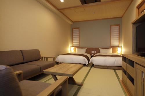 a living room with two beds and a couch at Onyado Yuinosho, Shirakawago in Shirakawa